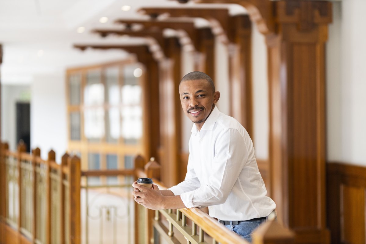 Black business man leaning over a railing at the office and smiling