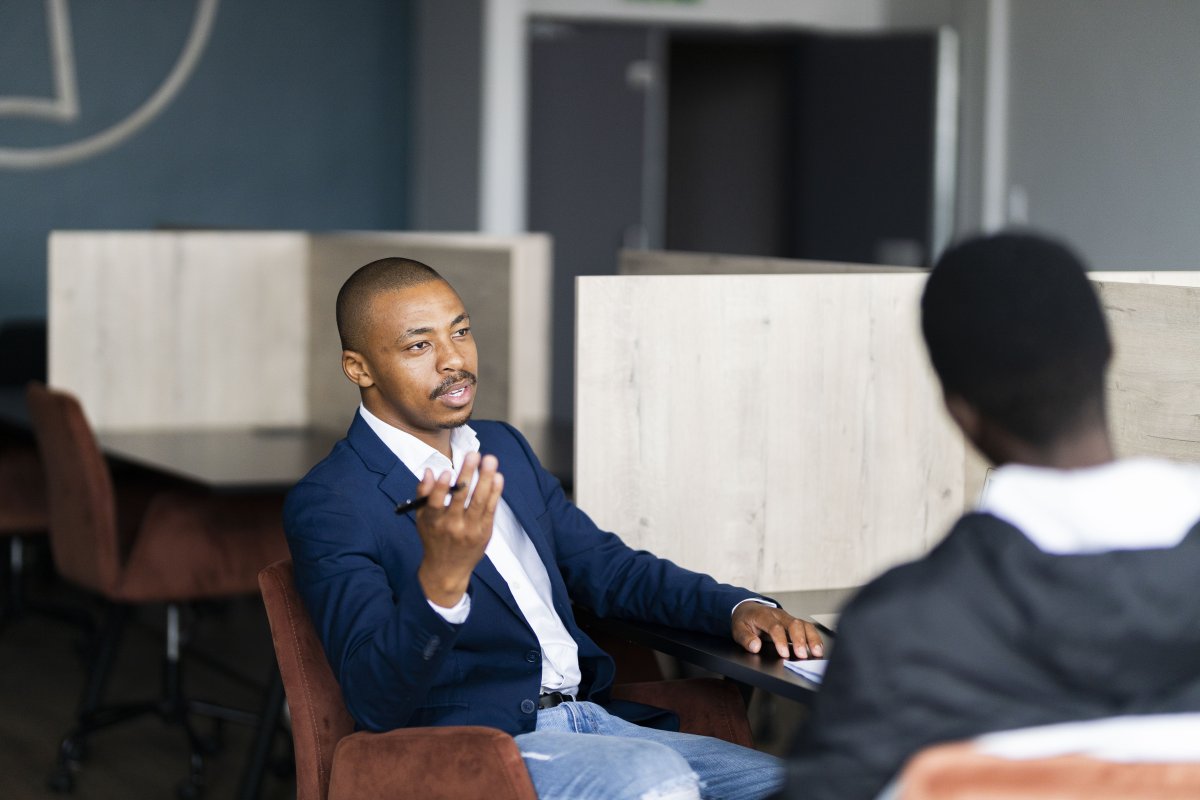 Black business man in a meeting with a client and talking while holding a pen