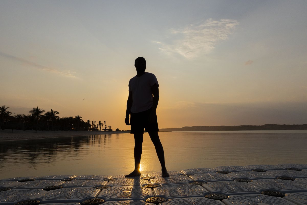 Silhouette of black man near a lagoon of water.