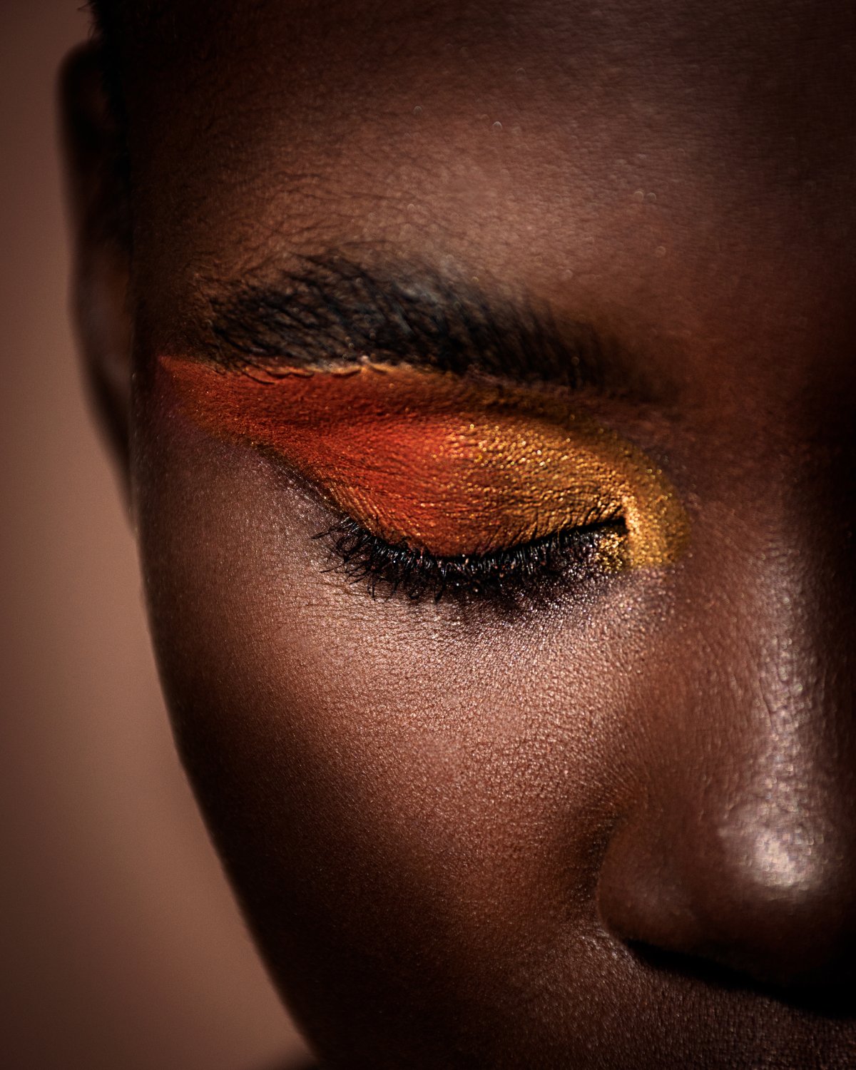 Portrait of an black African model with a dark melanin skin with yellow and orange eye make up on