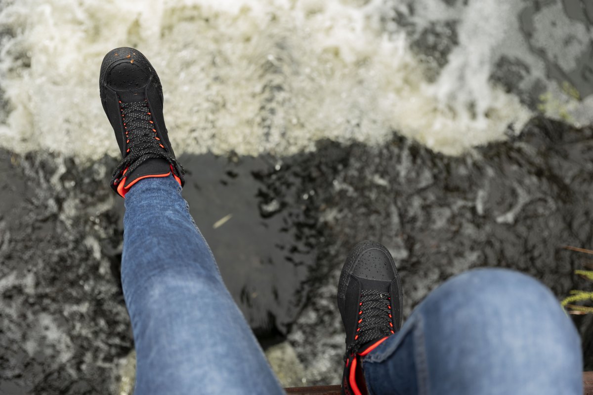 Black woman dangling feet by a river