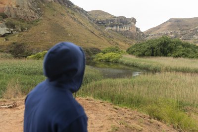 Black man sitting watching the mountains