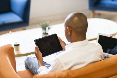 Black business man  working on a tablet and laptop from a coffee shop