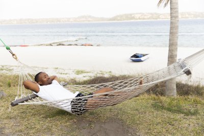 Black man laying on a hammock with a lagoon view.
