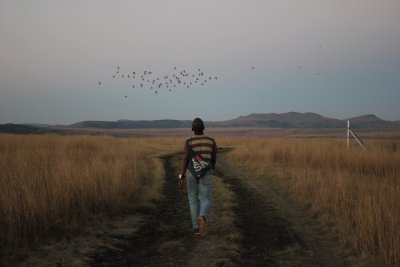 Black boy walking in the fields with birds flying
