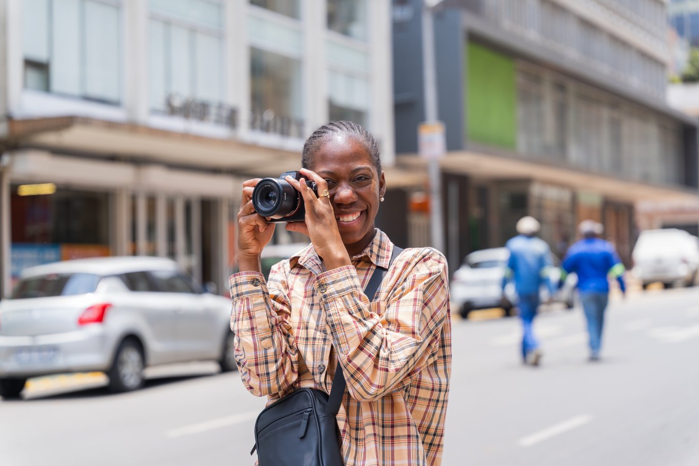 black woman photographer smiling in the streets with a camera