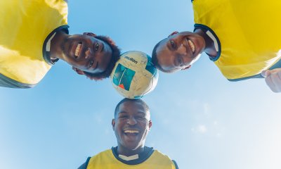 Soccer players smiling with a ball on their heads.