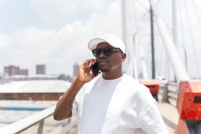 Black man using phone on nelson Mandela bridge wearing a white t-shirt