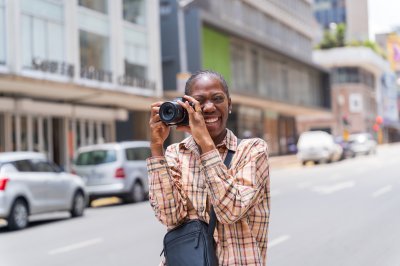 Black woman photographer smiling in the streets with a camera