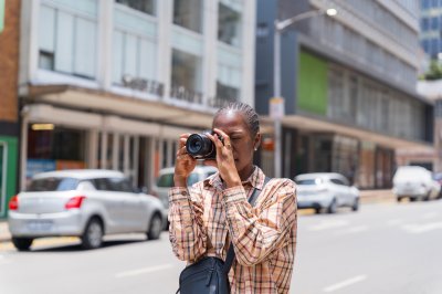 black woman photographer in the streets with a camera and bag
