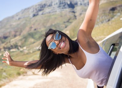 African woman smiling wearing glasses with hands in the air