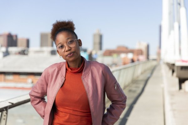African woman wearing a pink jacket looking at the camera