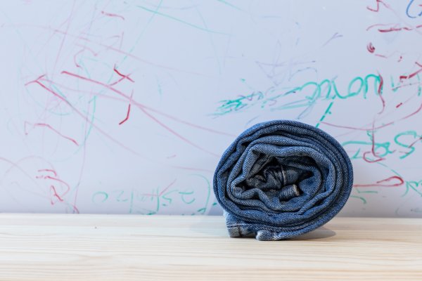 A pair of rolled jeans on a wooden table with graffiti background