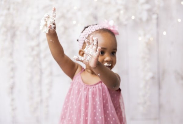 Black baby girl playing with cake