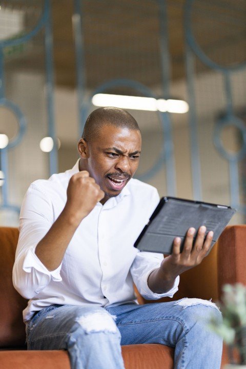Black man celebrating looking at ipad