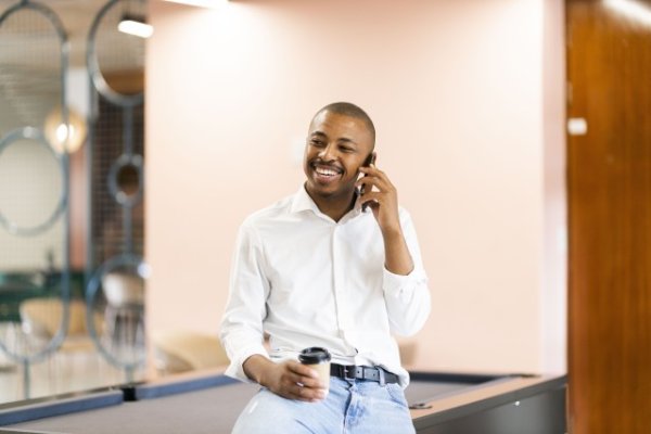 Black man talking on his cellphone by a pool table at work