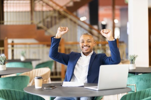 Black business man in a suit at work celebrating