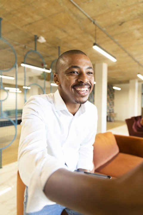 Black business man approaching to shake hands with a client at work smiling