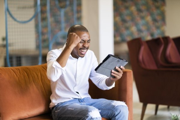 Black man celebrating and looking at ipad