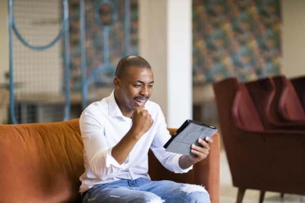 Black man celebrating and looking at ipad