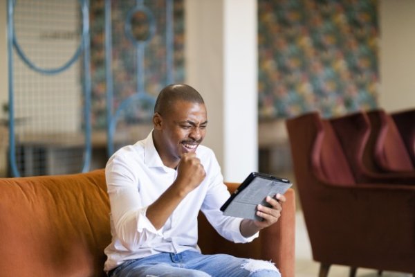 Black business man celebrating while looking at ipad