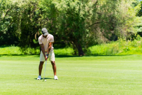 Black golfer wearing a pink shirt and a taylormade hat