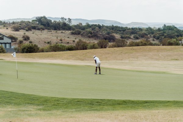 Black male golfer taking a putt on the green