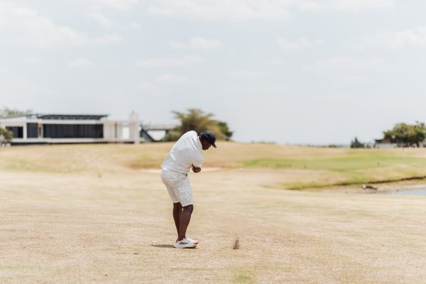 Black male golfer taking a swing at the green