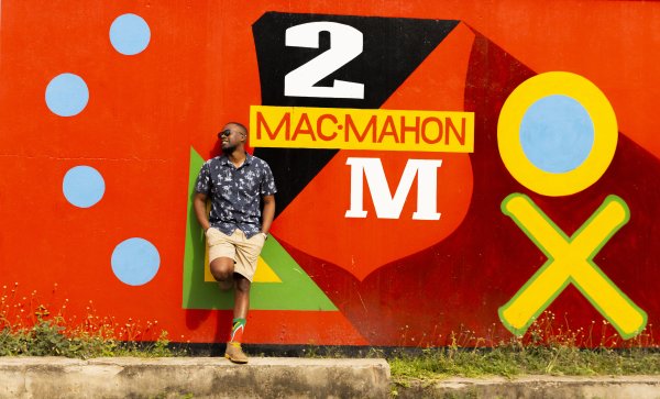 Black man near a 2M beer advert board.