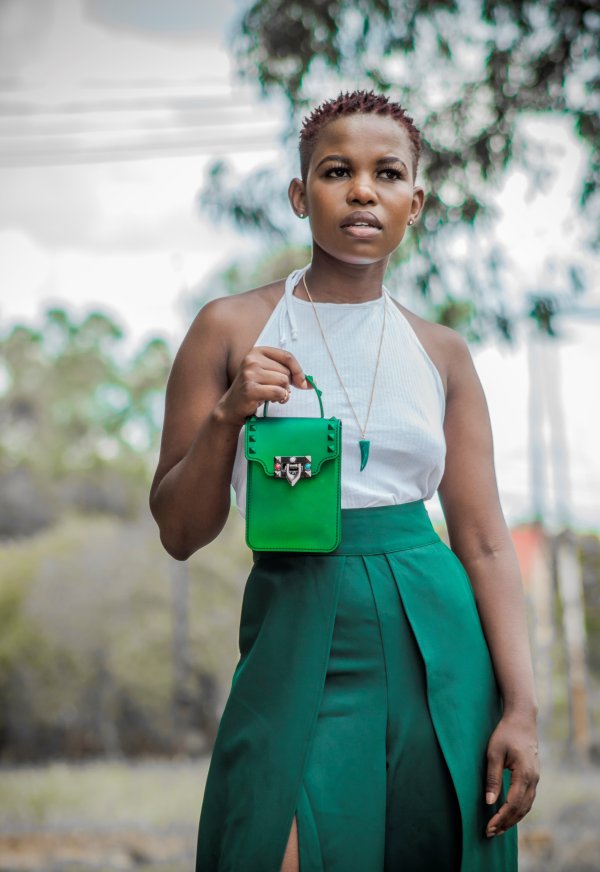 Black woman with short hair carrying a green bag