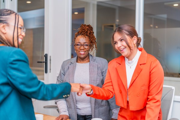Business women with handshake, lawyer and client with deal, contract and partnership. Mature woman smiles looking at camera.