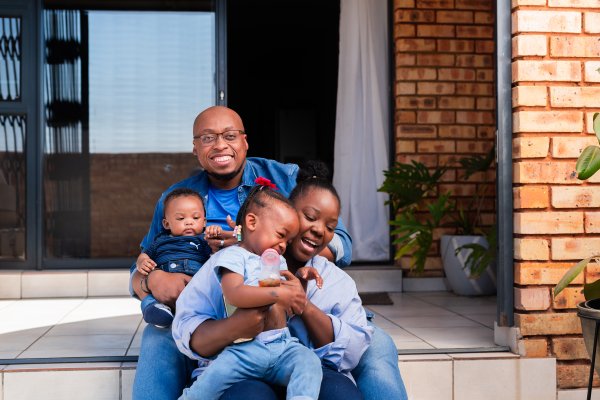 Happy black family at home bonding on a sunny day, all wearing blue clothes.