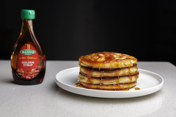 Pancakes on a plate next to golden syrup bottle