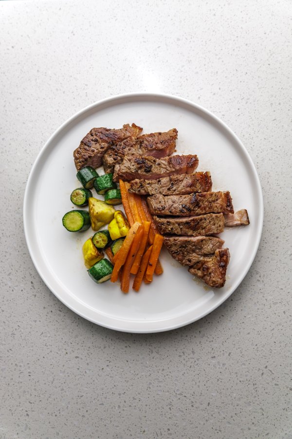 flatlay of well cut steak and vegetables on a plate for dinner