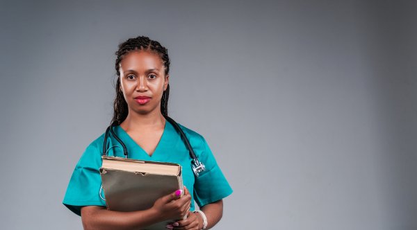 Portrait of young doctor holding books in studio.