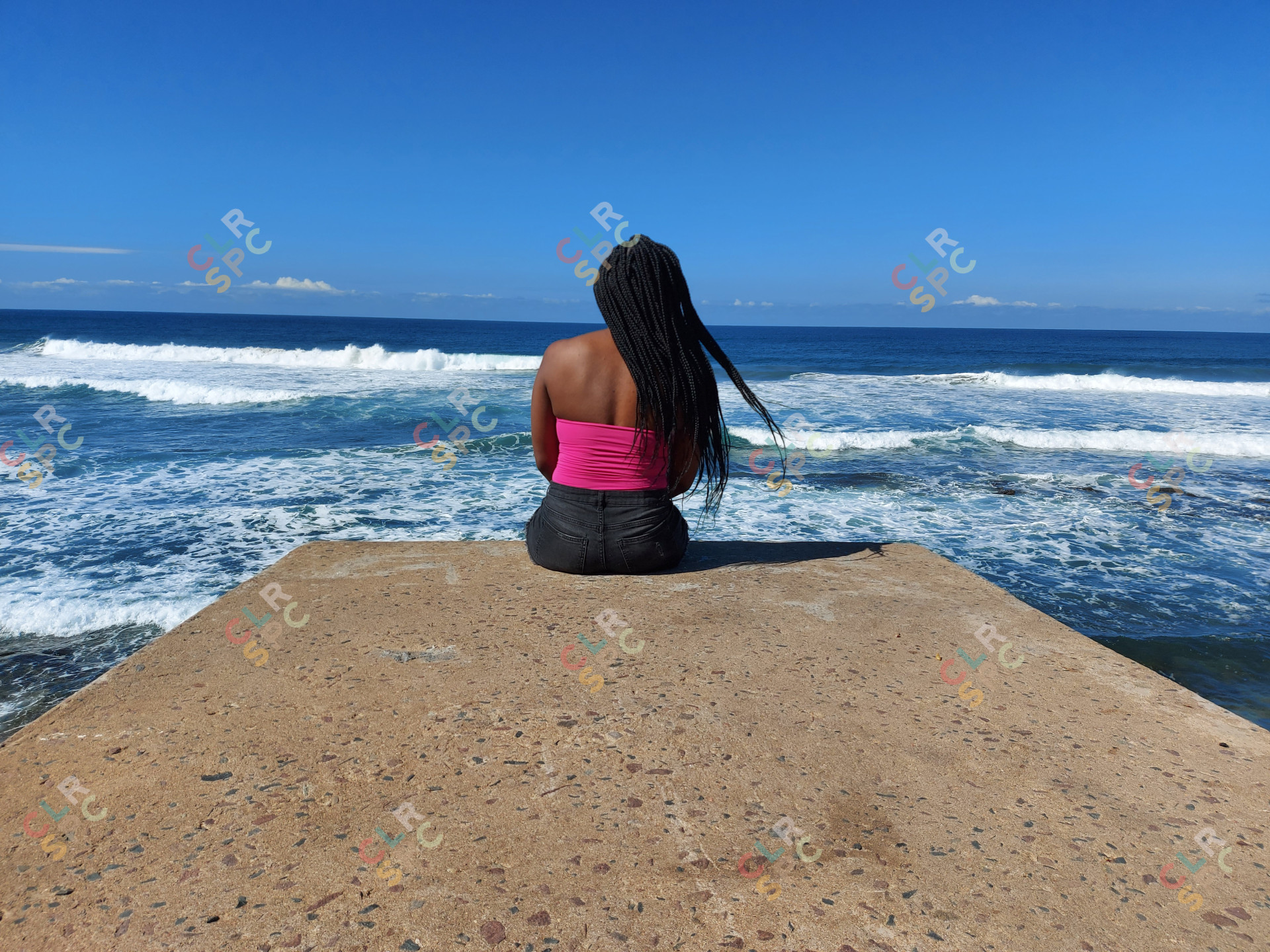 Woman sitting on the beach rock, taking in the breeze