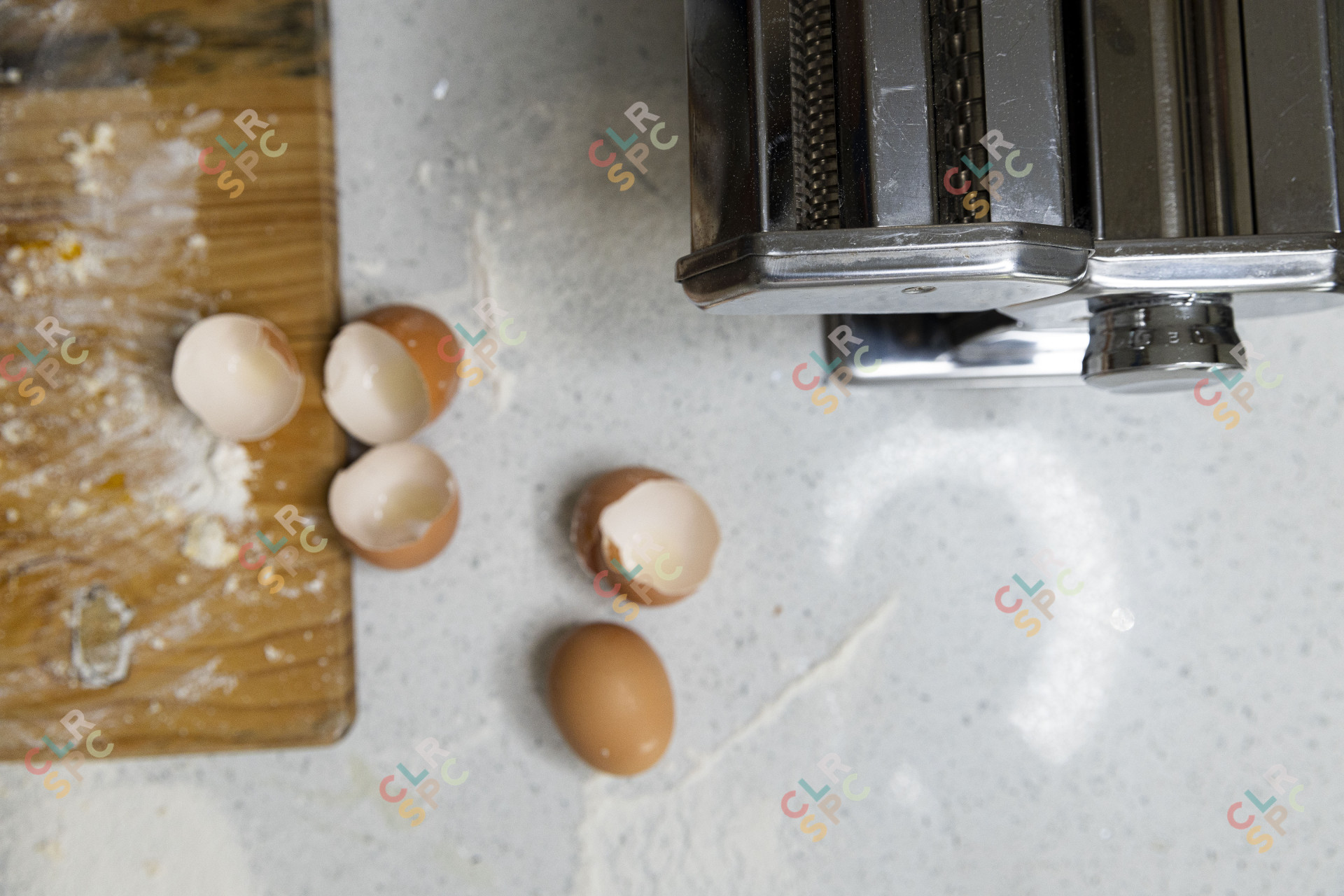 Egg shells on a table next to a pasta maker