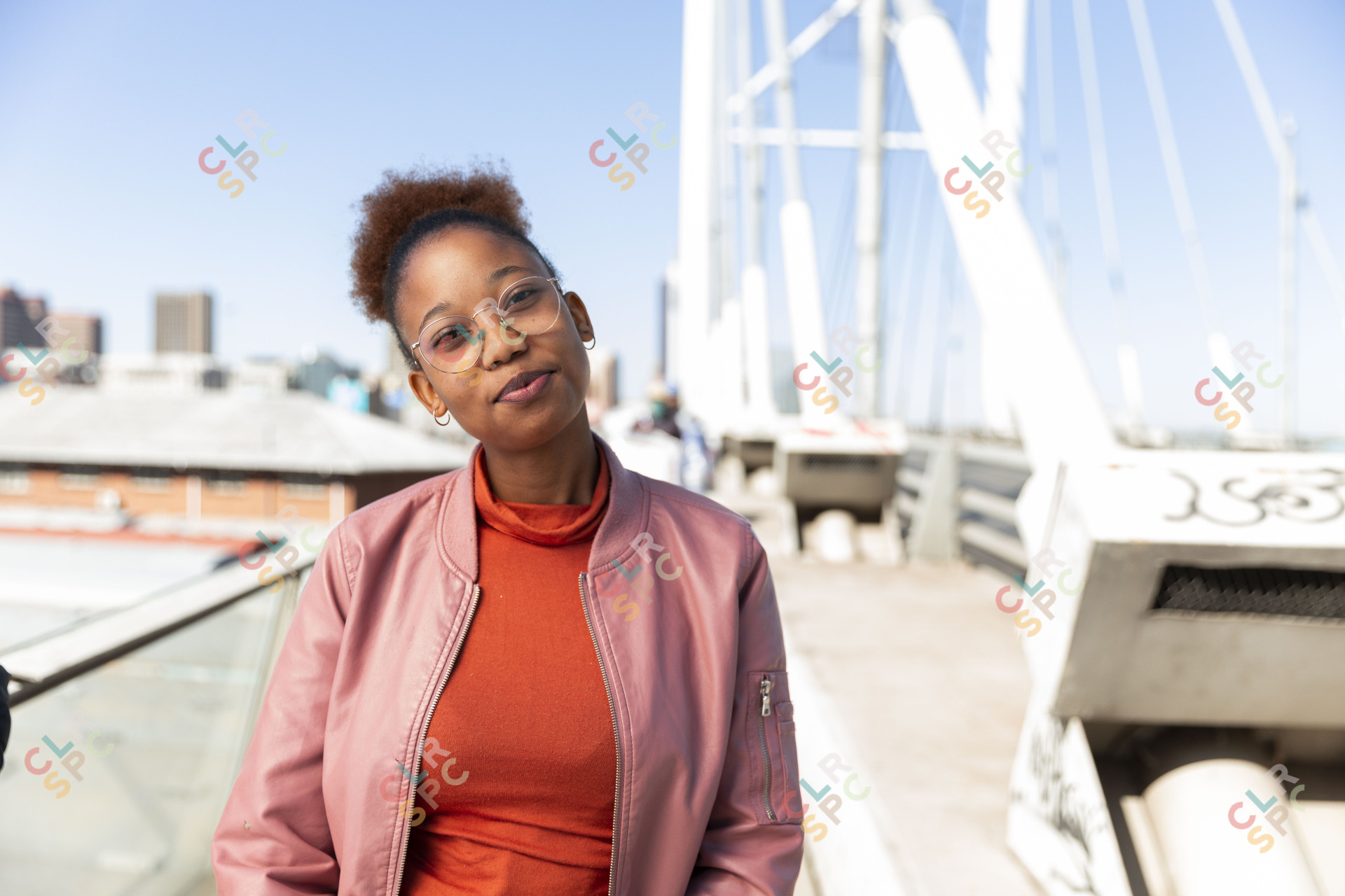 African woman wearing pink jacket on Nelson Mandela bridge grinning