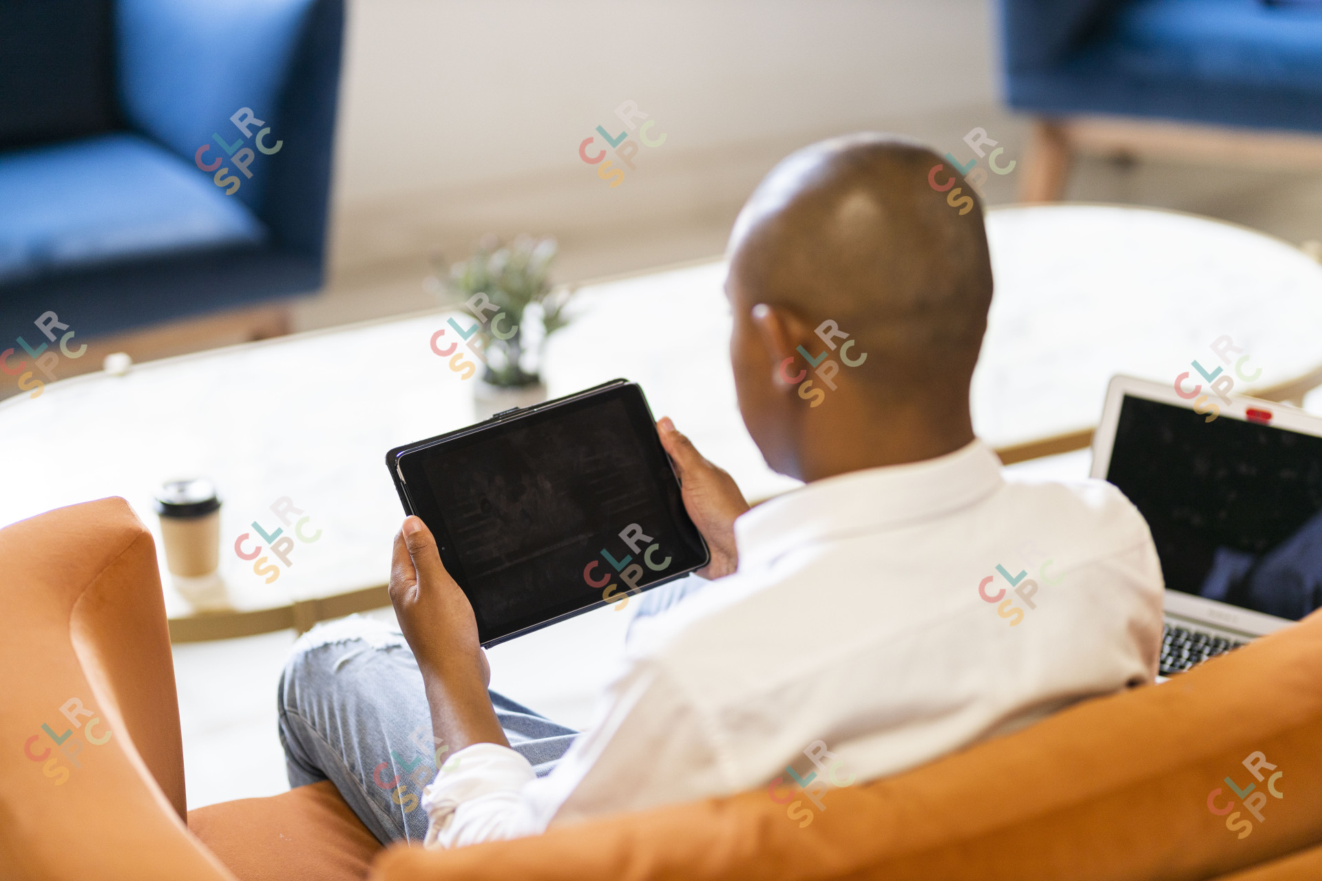 Black business man  working on a tablet and laptop from a coffee shop