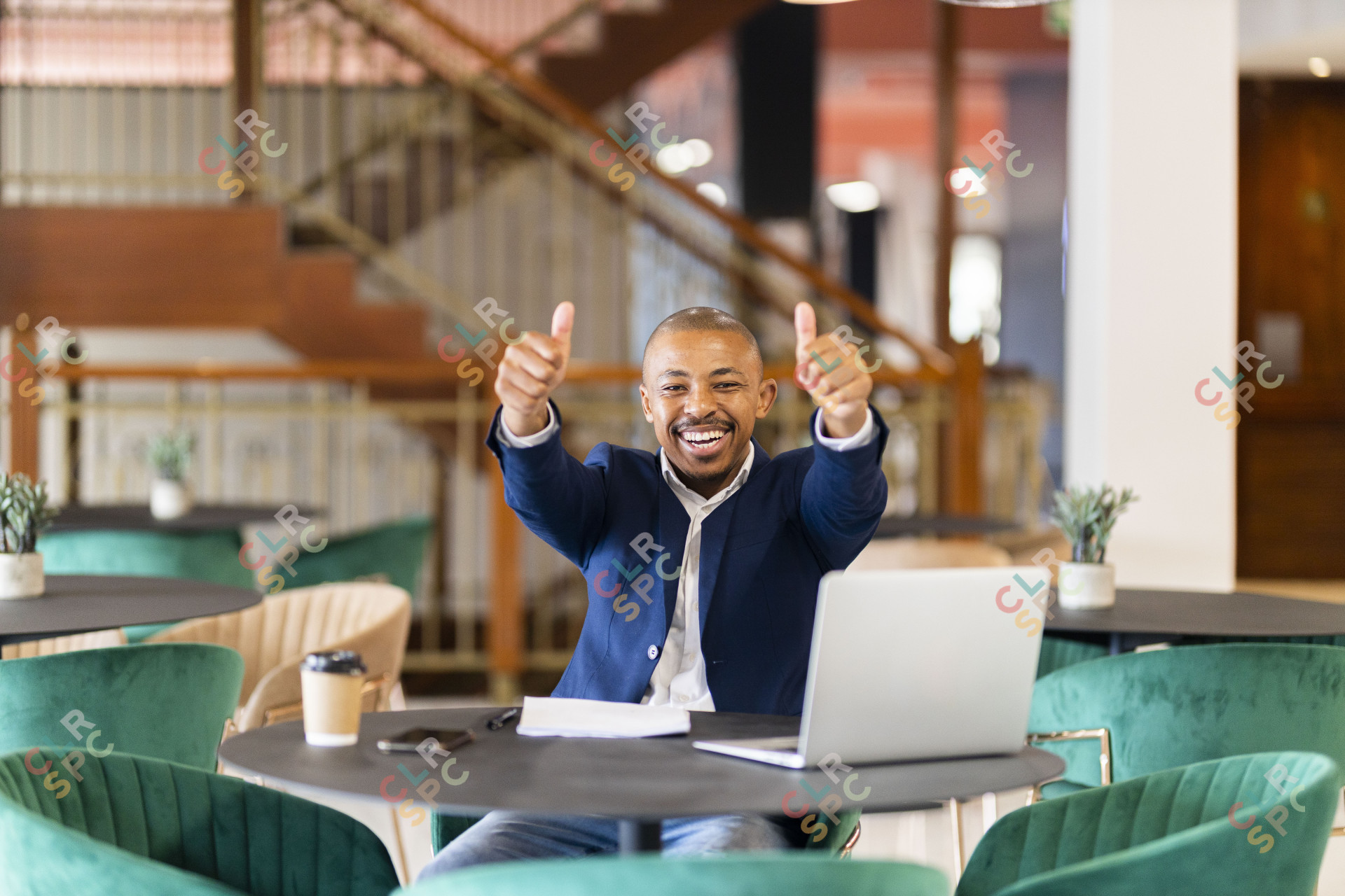 Black business man holding thumbs up at the office with a smile on his face