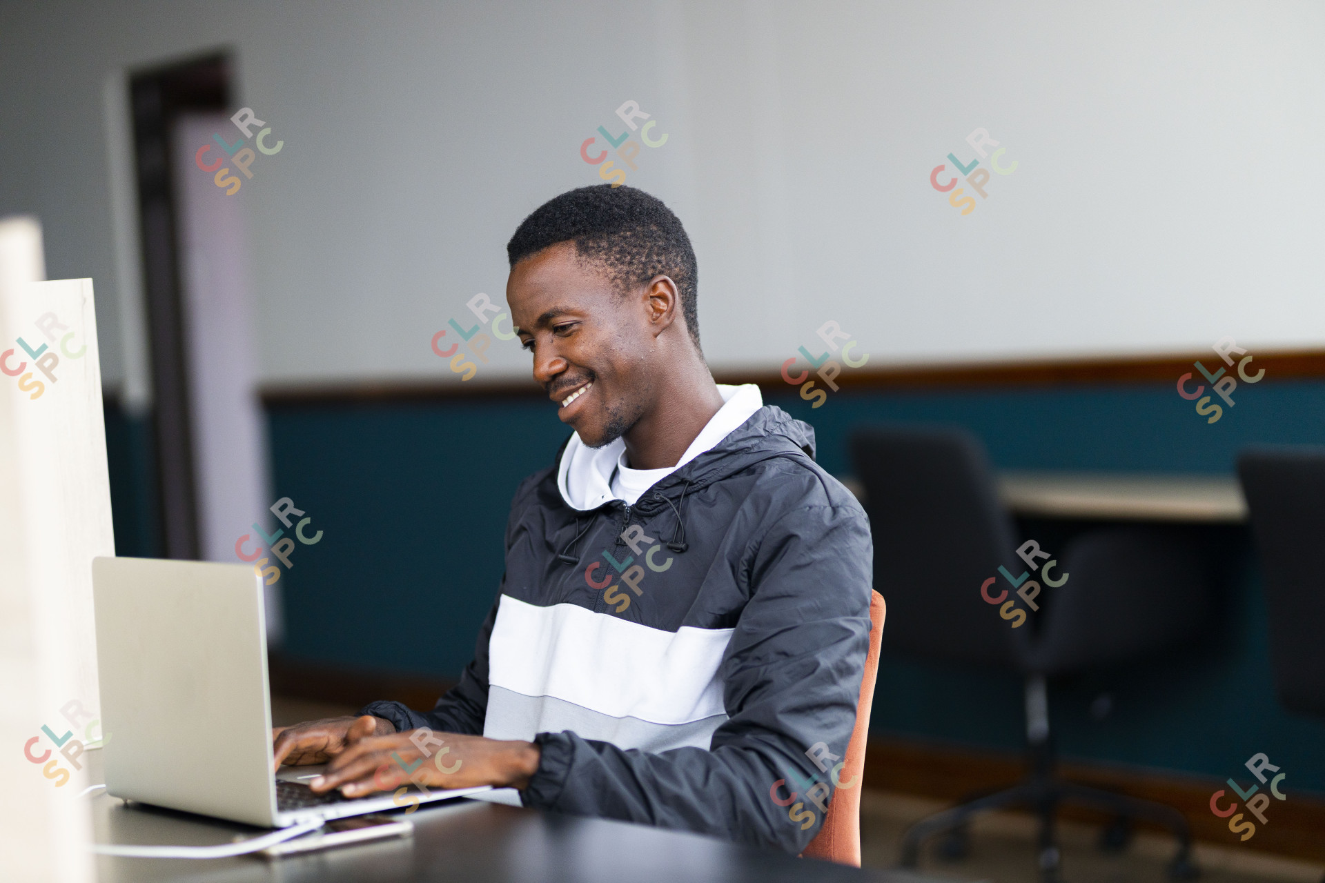 Black man looking at his laptop with a grin on his face