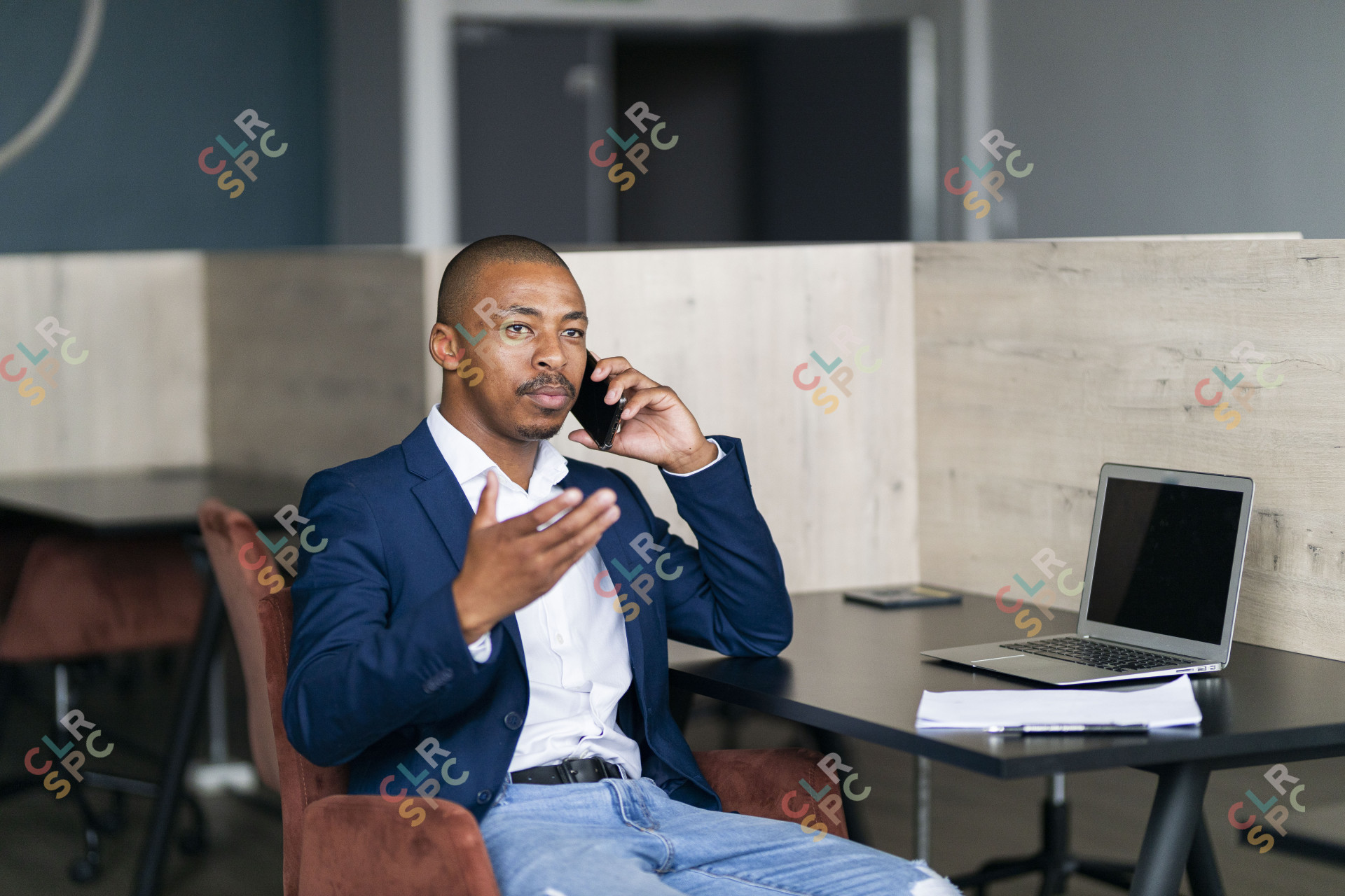 Black business man talking on his phone and wearing a suit at work