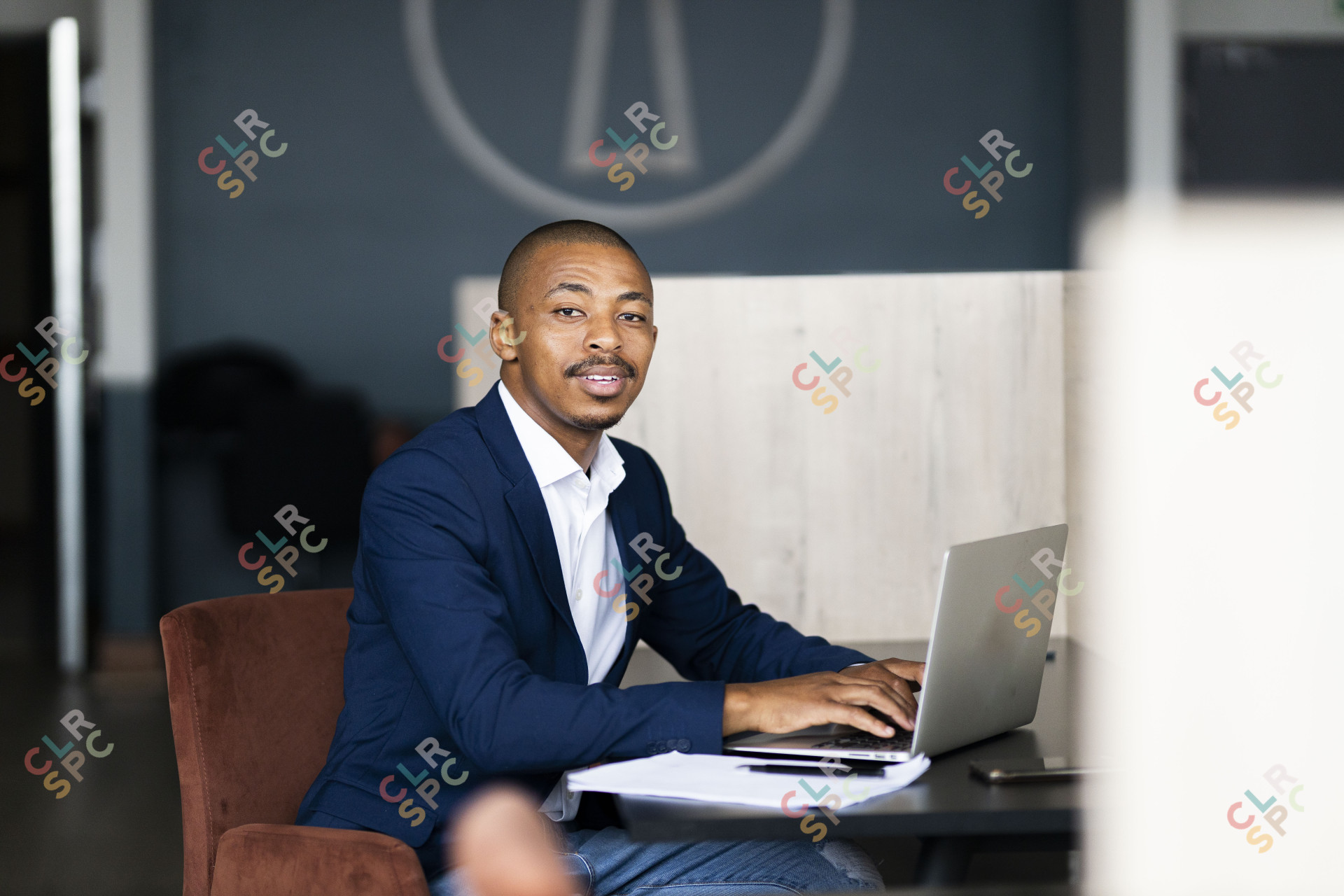 Black business man looking at the camera while working on his laptop