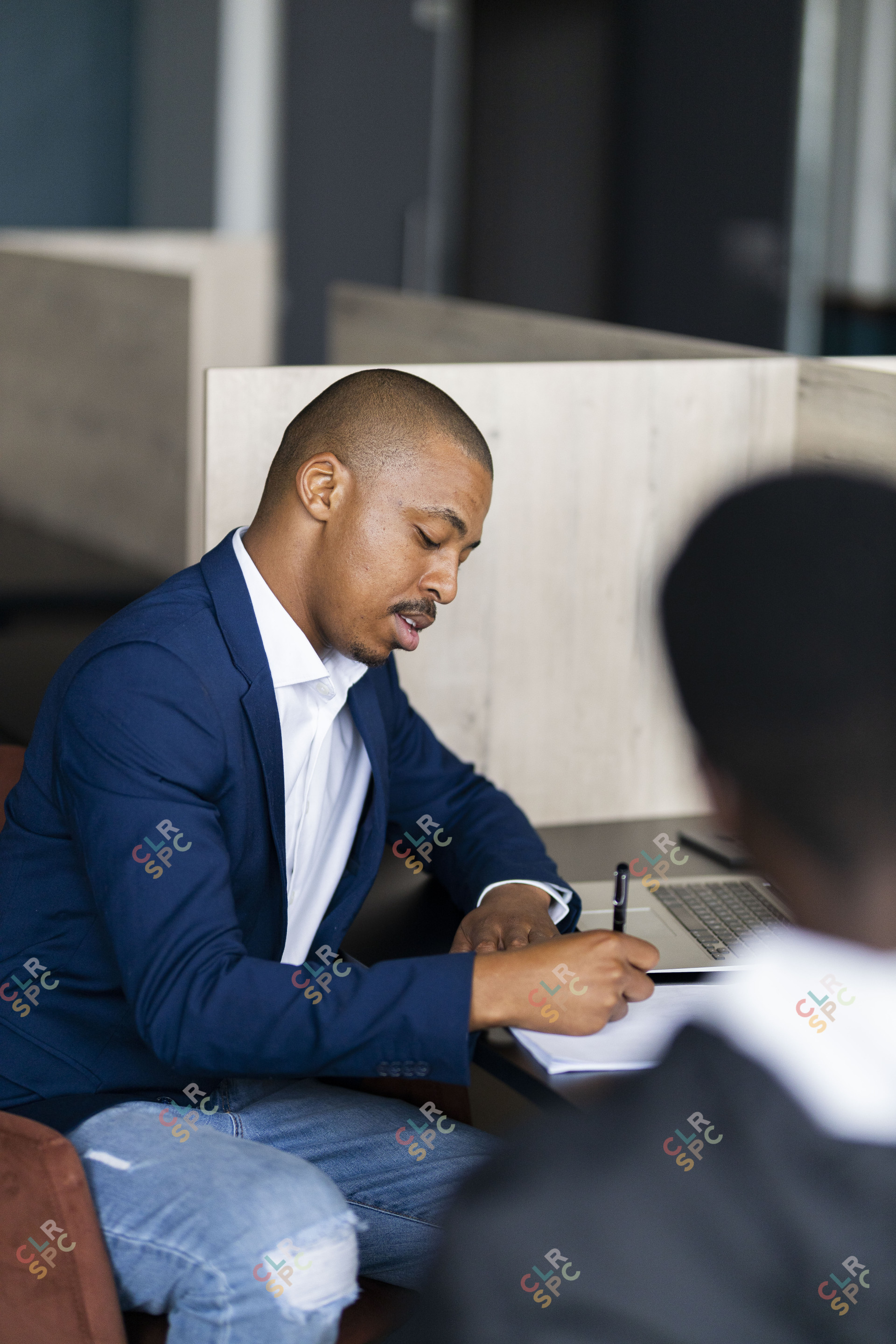 Black business man wearing a suit and writing down notes.