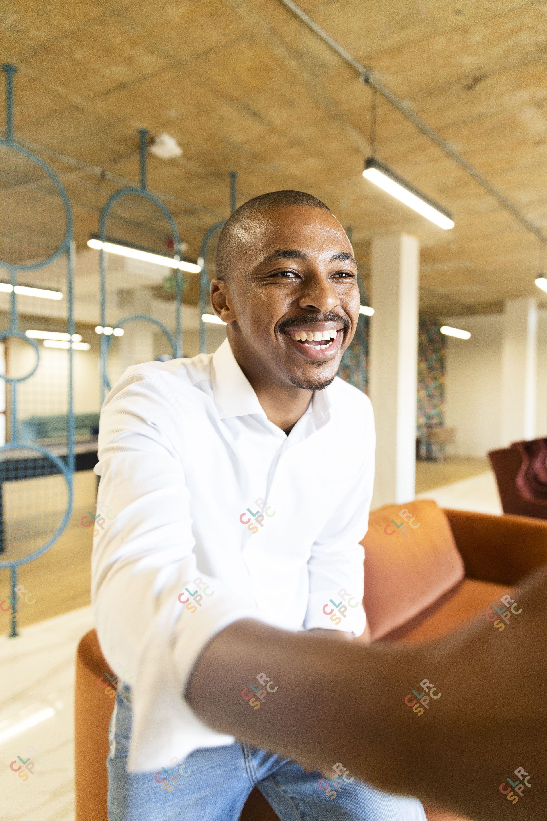 Black business man wearing jeans approaching to shake hands with a client at work while smiling