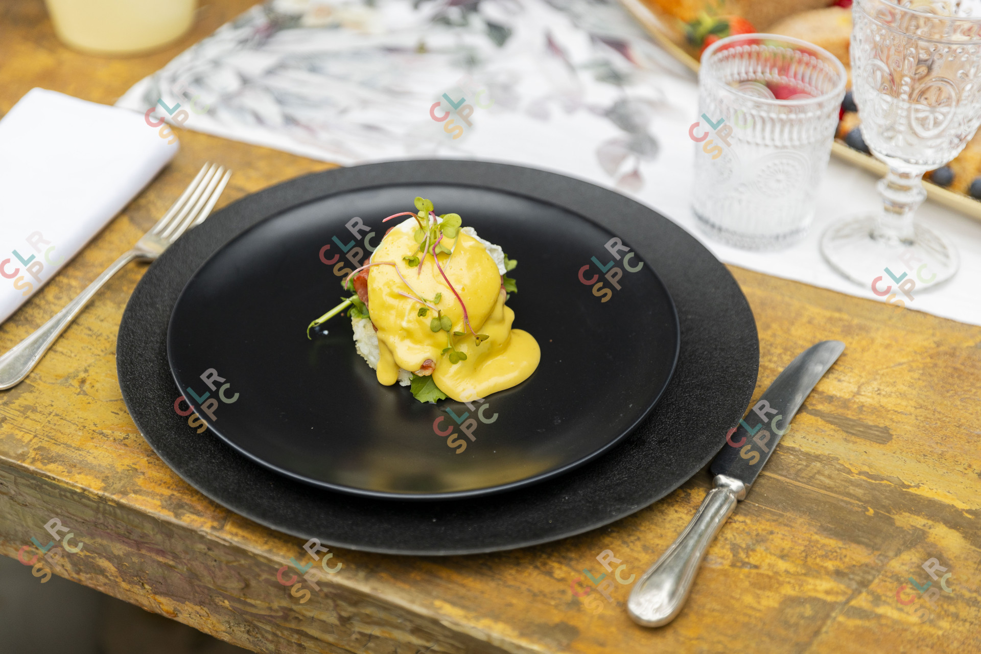 Eggs benedict on a black plate.