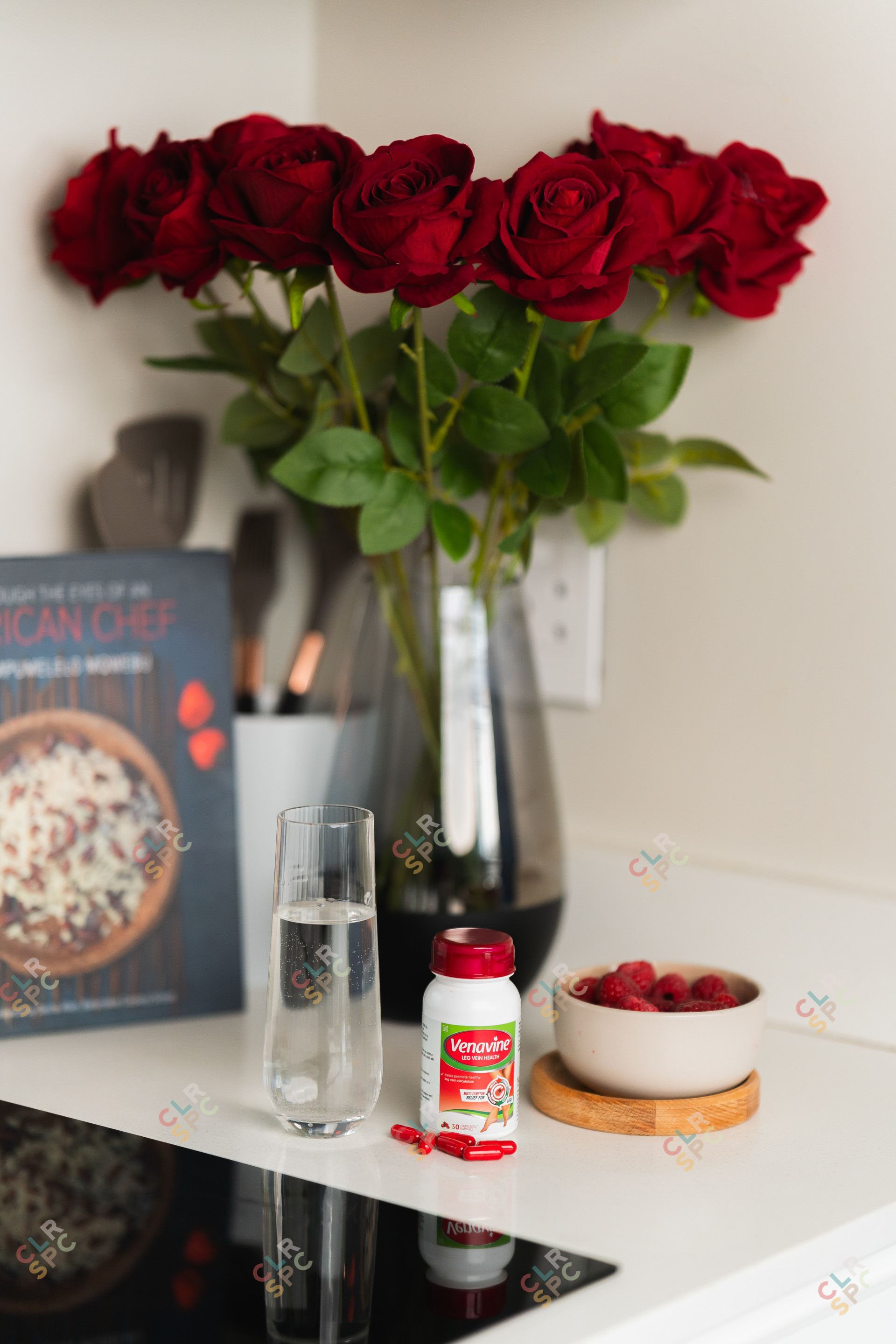 Health products on a marble table with flowers and food books behind.