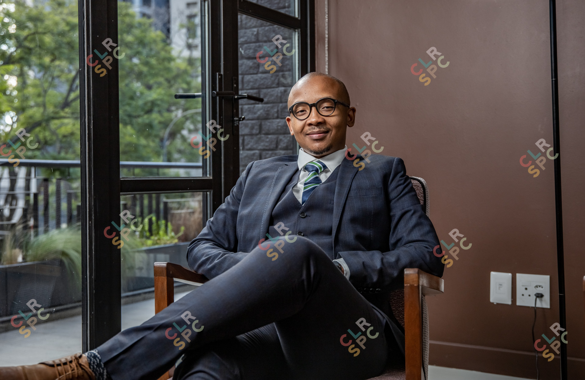 Black businessman sitting on a chair smiling with a suit on.
