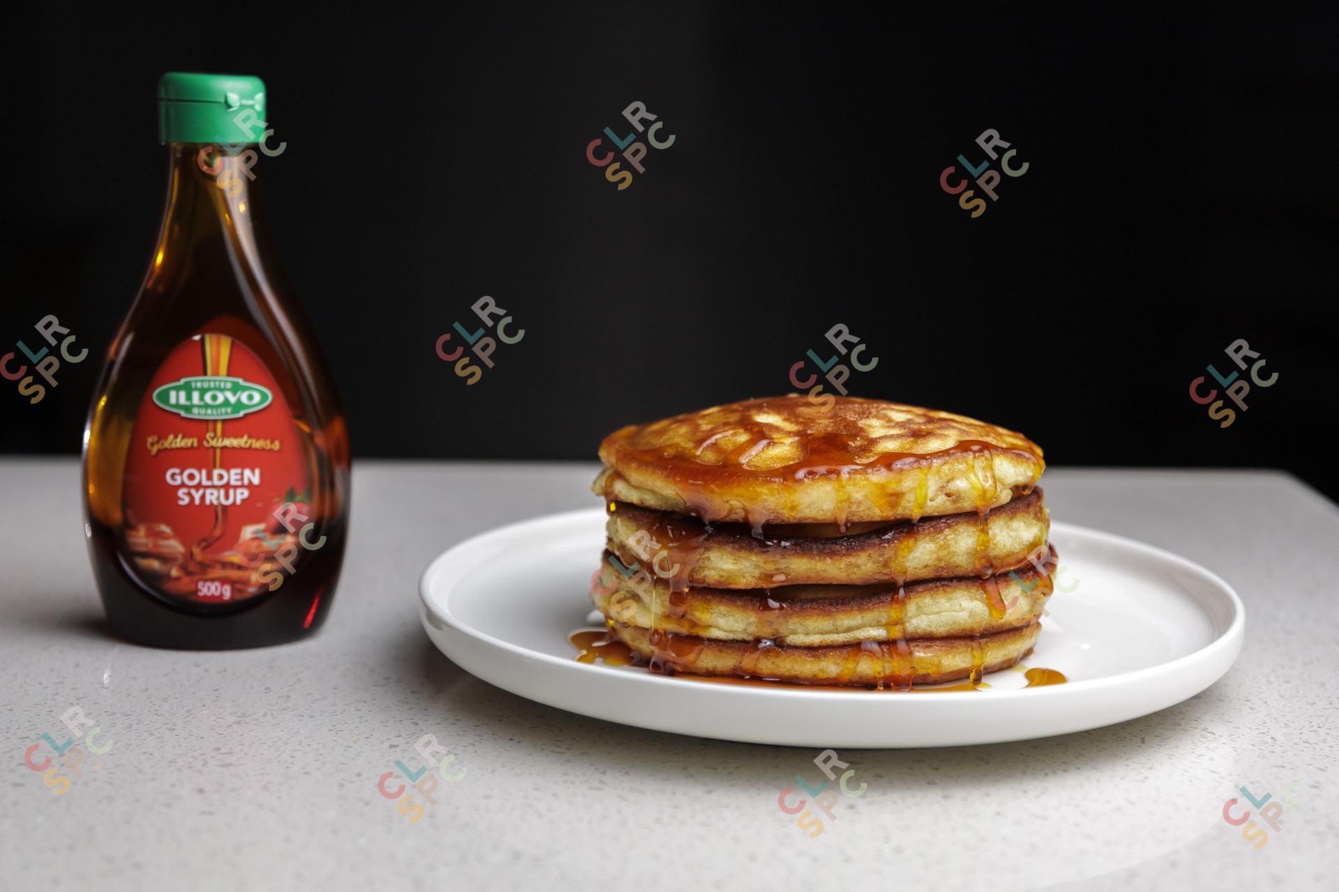 Pancakes on a plate next to golden syrup bottle