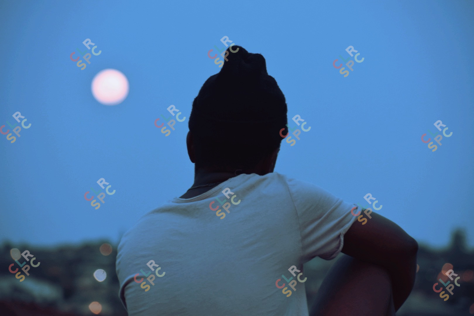 A boy sitting on the fence admiring the sky light
